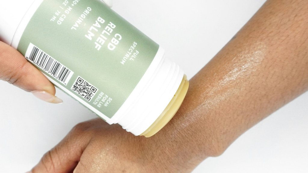 Hand applying CBD relief balm directly onto forearm, highlighting the smooth, moisturizing application of the full-spectrum product.