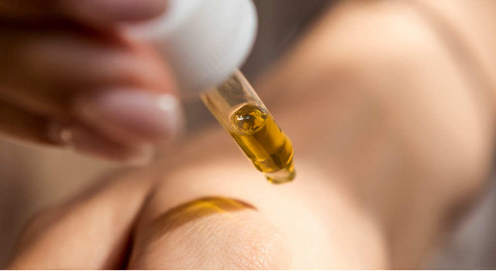Close-up of a hand applying CBD oil with a dropper onto skin, highlighting the smooth, golden liquid and gentle skincare application.