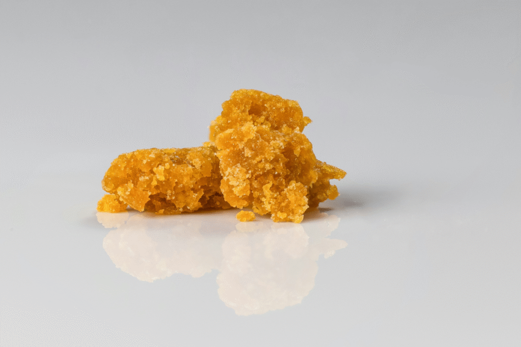 still image of golden cannabis concentrate on a white shiny background