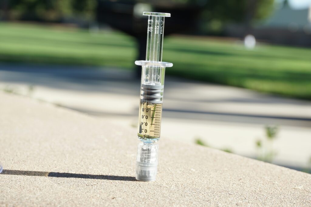 image of cannabis distillate syringe on the ground outside