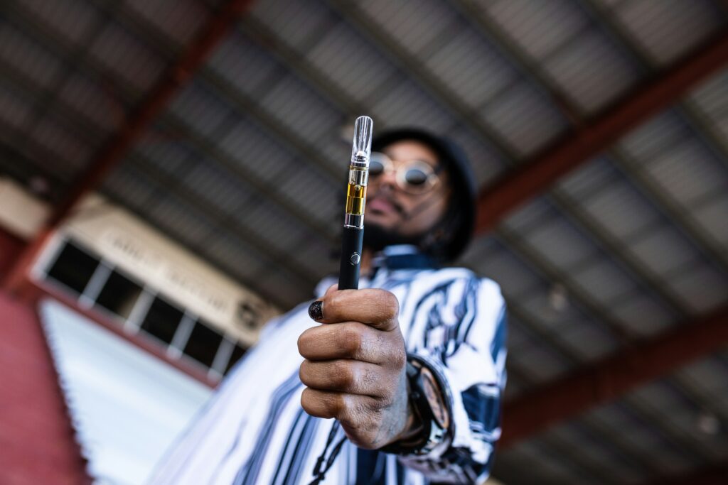 image of an out of focus man holding a cannabis cart and battery