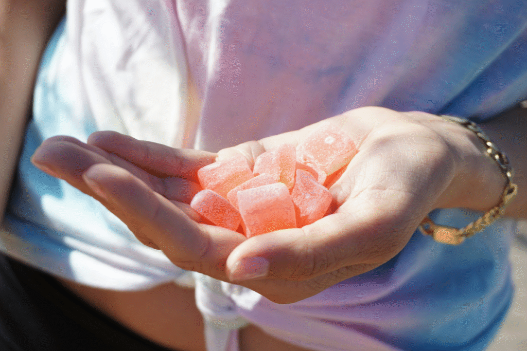 image of a person's hand holding a pile of orange cannabis gummies