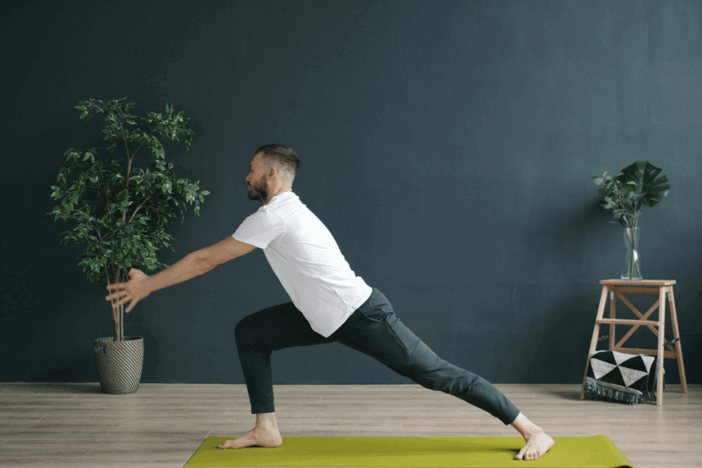 - Nature Med Dispensaries A man practicing a deep lunge on a yoga mat in a minimalist studio, demonstrating how cannabis-assisted yoga can improve flexibility and athletic recovery.