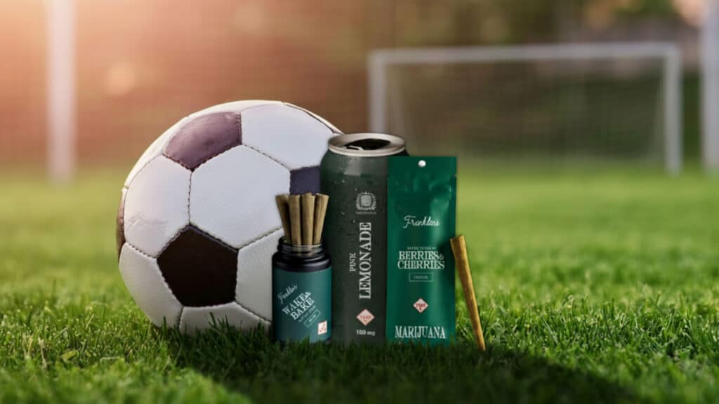 Soccer ball beside cannabis product boxes and a vape bottle on a grassy field.