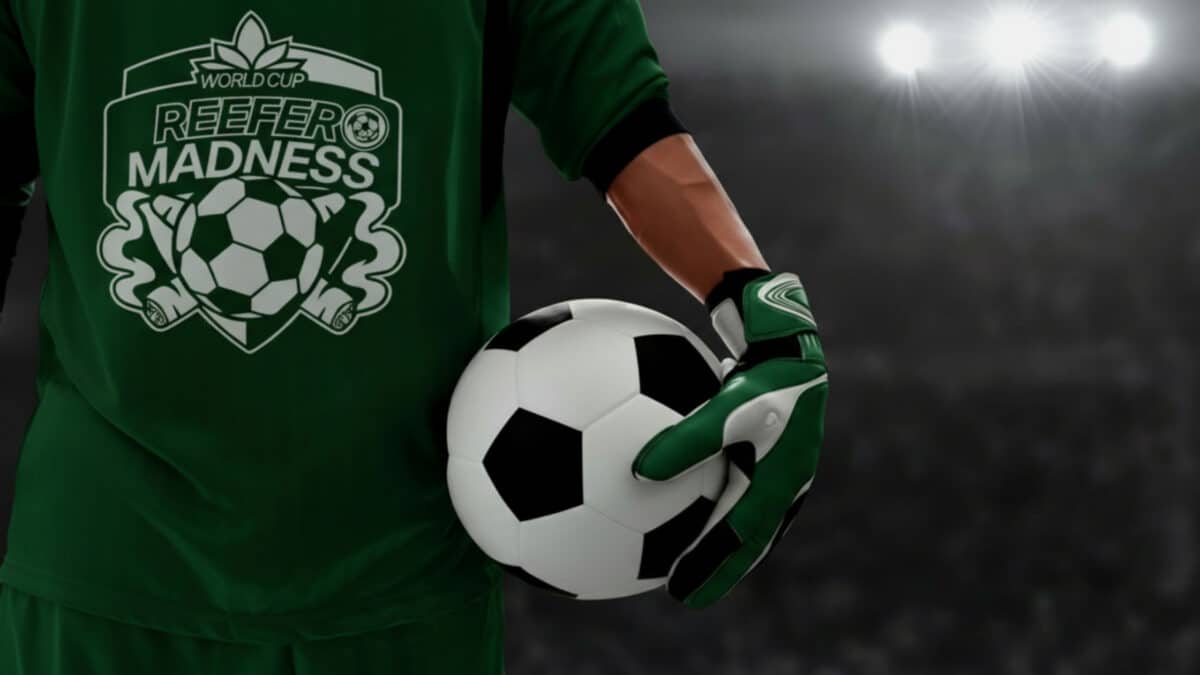 Soccer goalkeeper in a green jersey holding a soccer ball, stadium lights in the background.